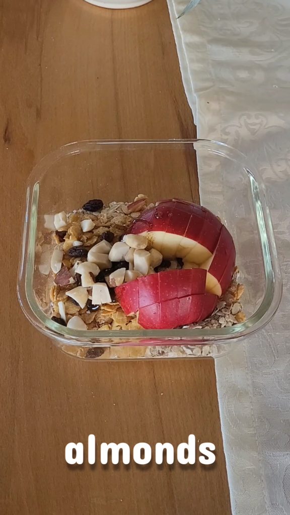 Microwave apple oatmeal and apple pieces in a bowl with nuts before cooking.