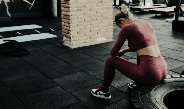 woman sitting exhausted in gym after workout lost motivation to work out
