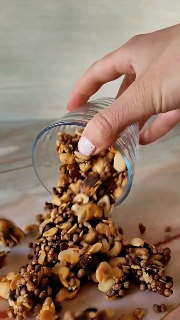 homemade crunchy granola with soy flakes, peanuts and chocolate being poured out
