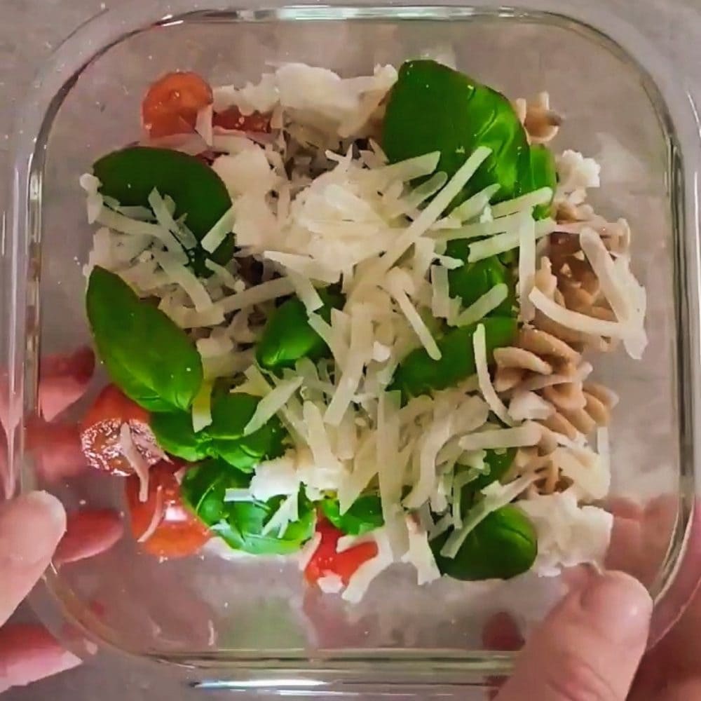 Leftover pasta made in a microwave bowl with tomatoes, cheese and basil