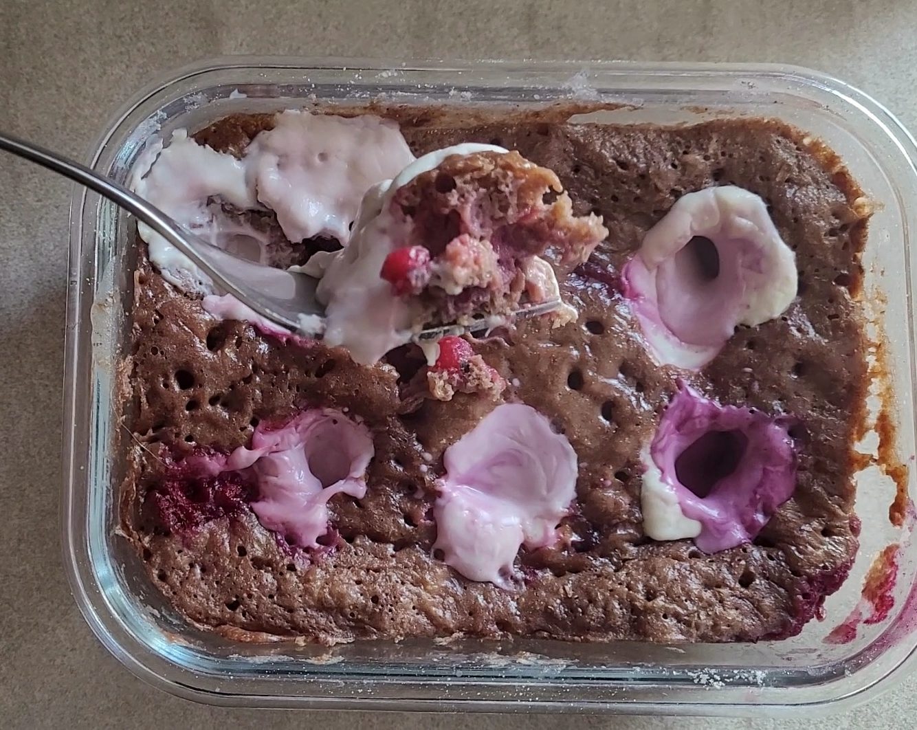 Close-up of a microwave cheesecake in a glass bowl with pink and white toppings.