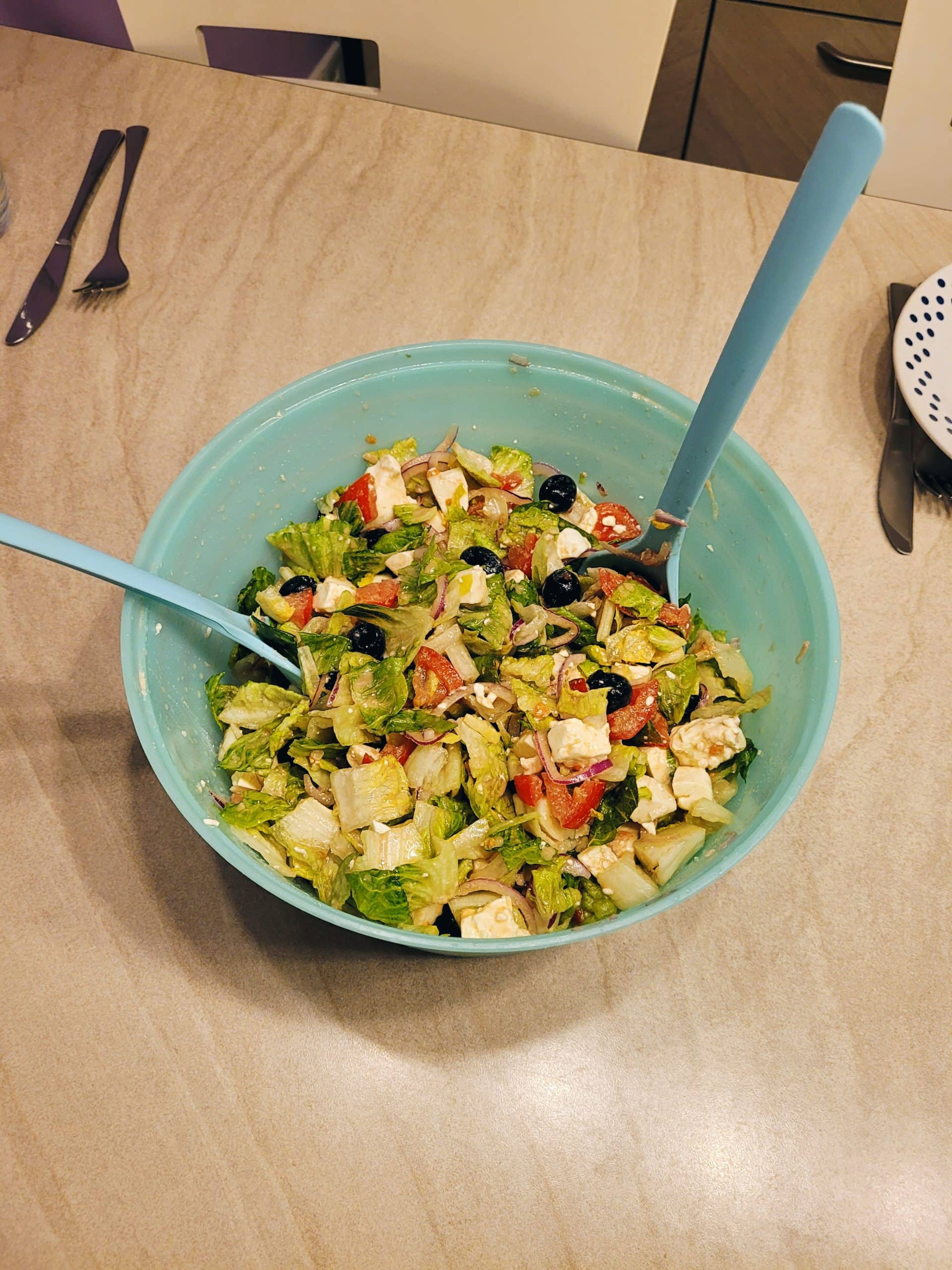 Healthy Greek salad with feta, mozzarella, and fresh vegetables in a blue bowl.