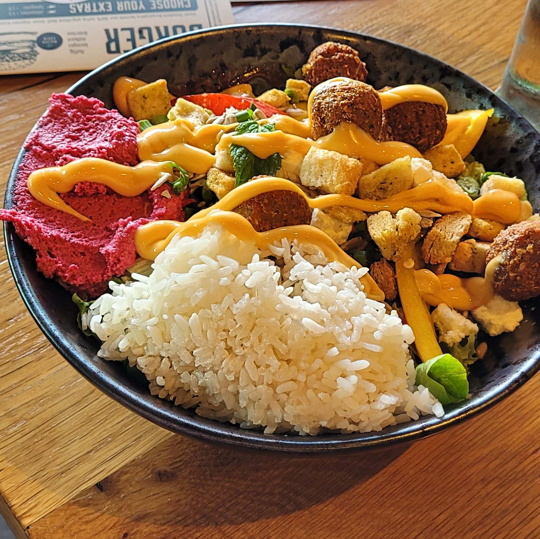 Healthy bowl with rice, humus, falafel, mango sauce, avocado and crutons 