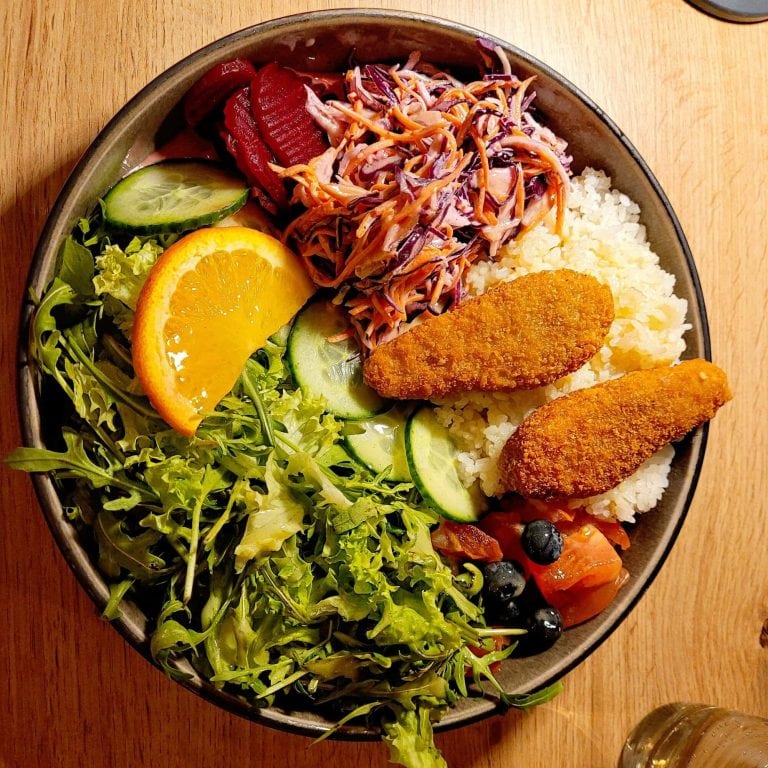 Healthy Mediterranean salad with fish, fresh vegetables, and citrus slices for a nutritious meal.