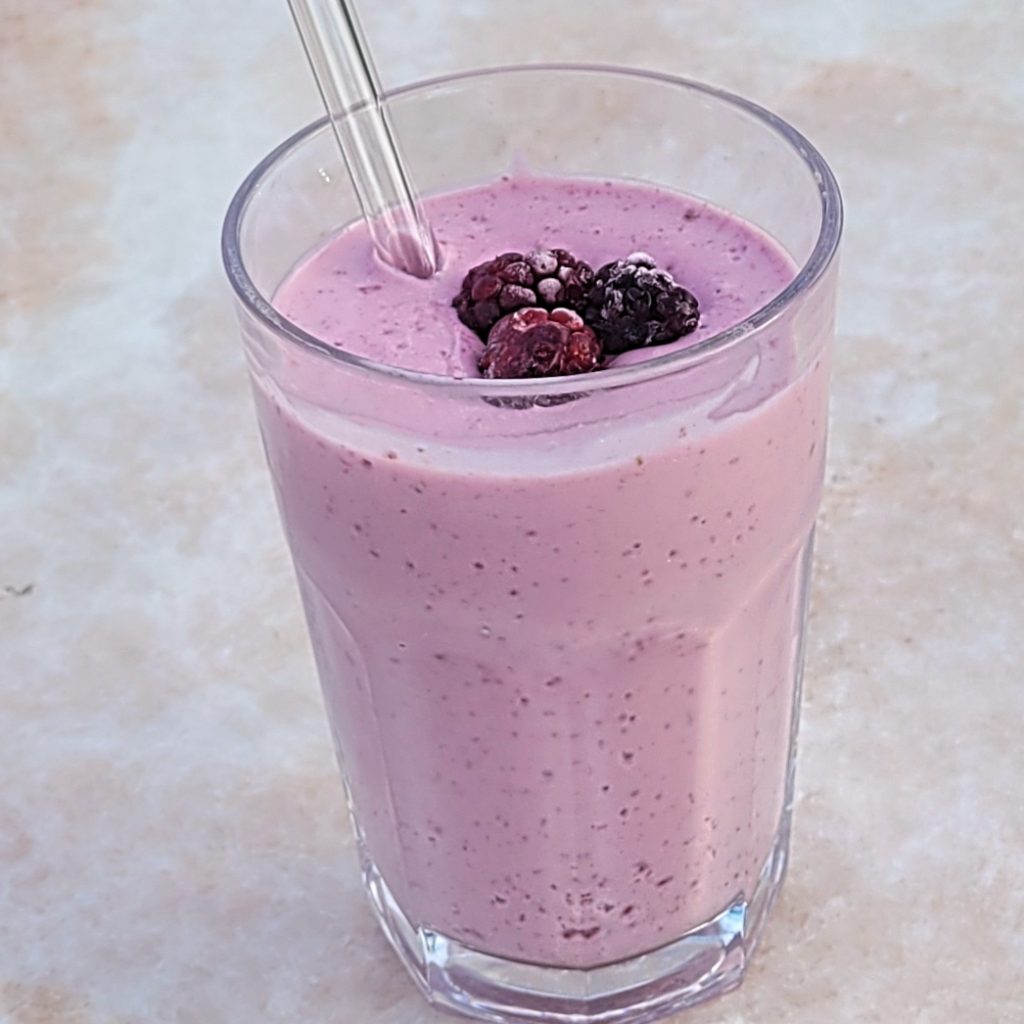 Creamy raspberry protein shake in a glass with fresh raspberries
