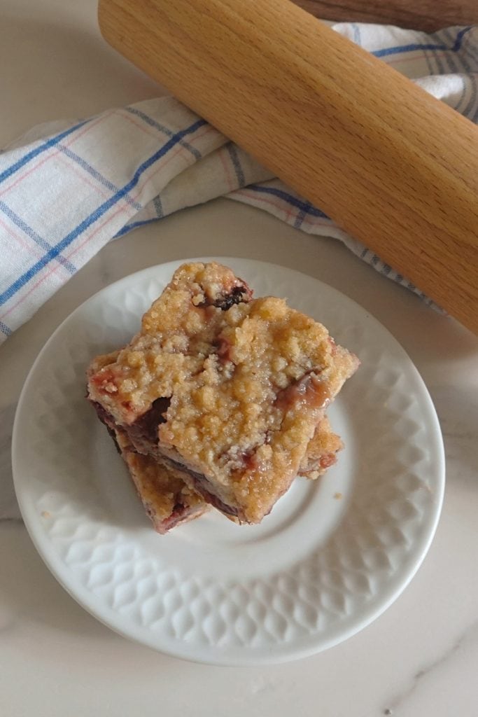 Homemade German plum crumble cake squares with whole wheat streusel served on a white dessert plate