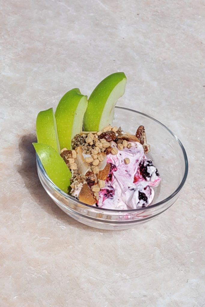 Fruit and Greek yogurt bowl with berries, granola, and apple slices.