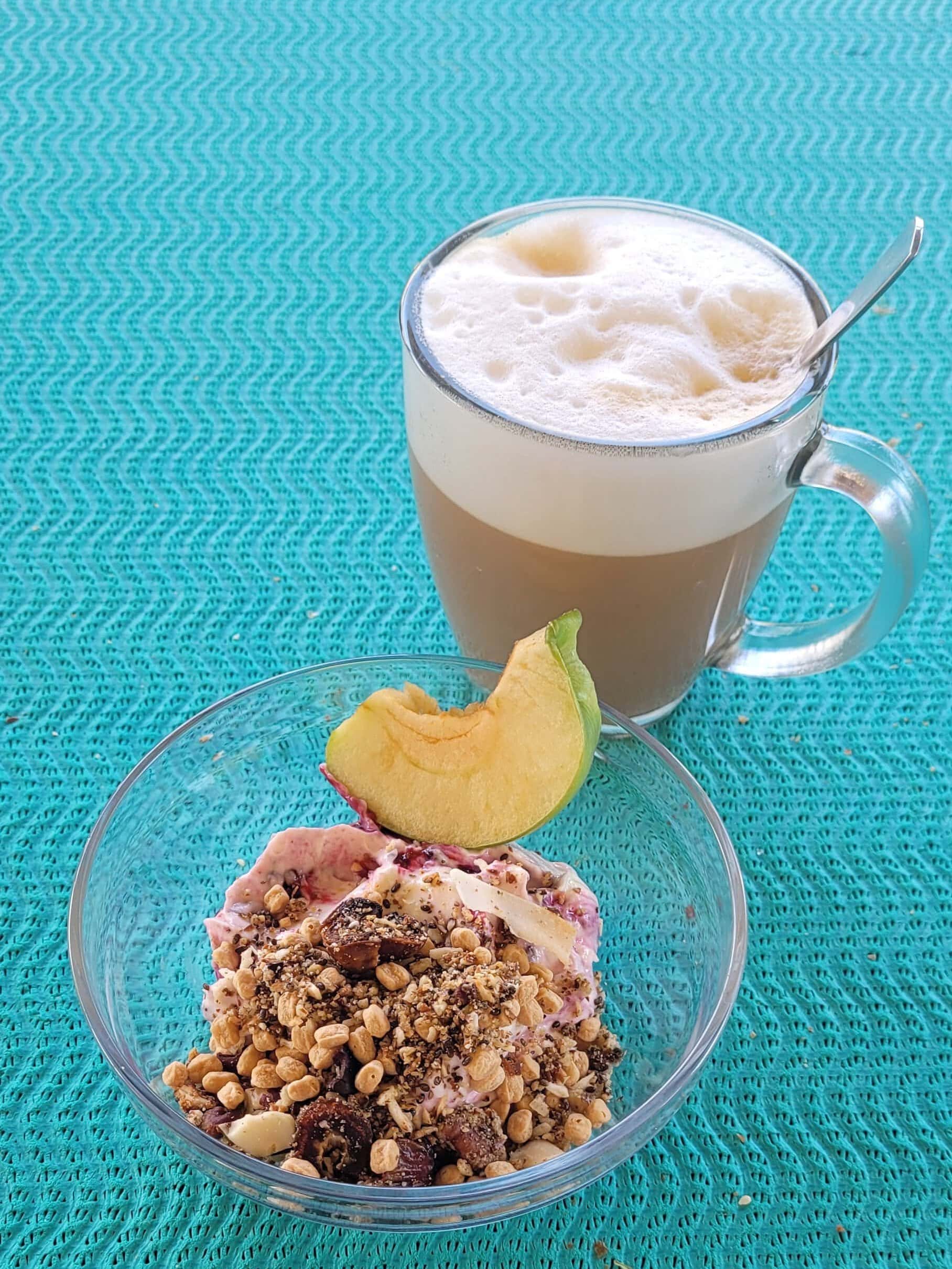 Greek yogurt breakfast bowl with fruit, granola, and coffee.