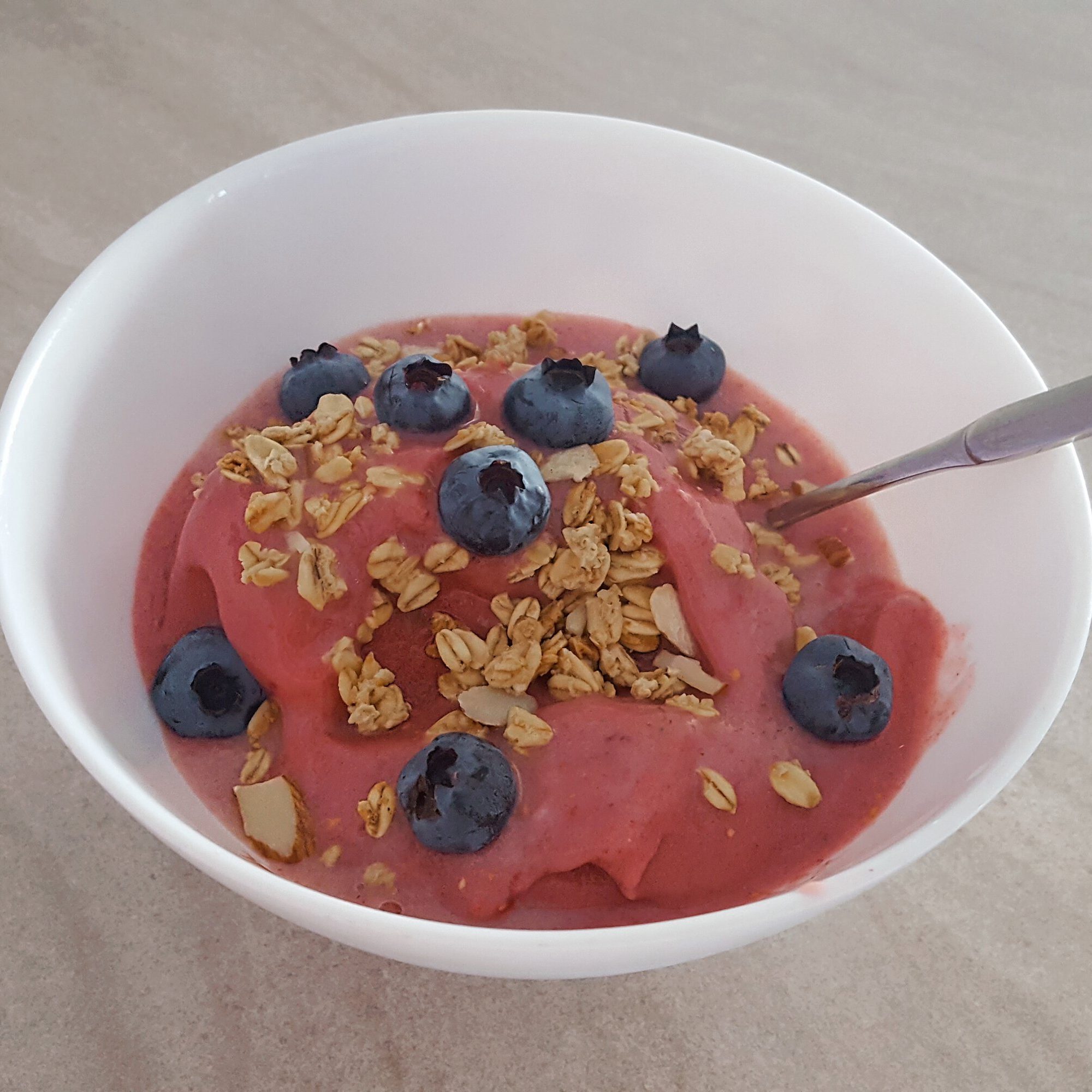 Strawberry Greek yogurt bowl topped with blueberries and crunchy granola.