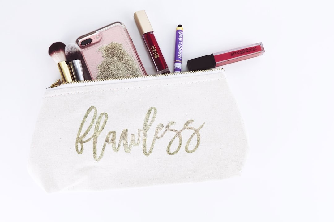Makeup bag with brushes, lip gloss, and phone for beauty and skincare essentials.