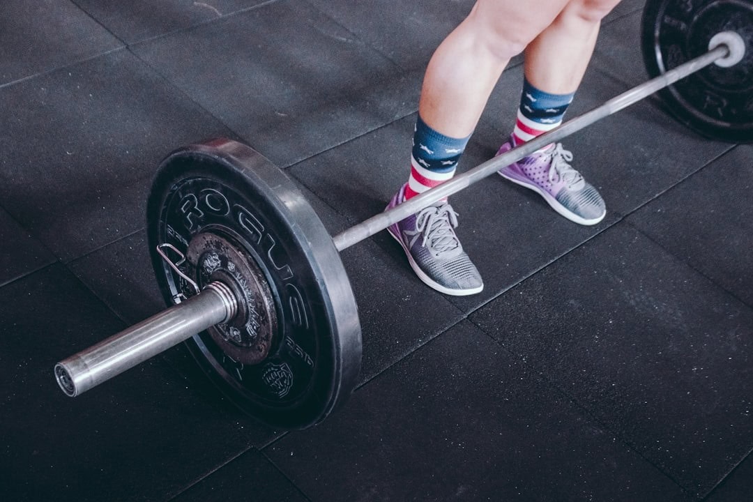 Woman lifting a barbell with weights during strength training workout.
