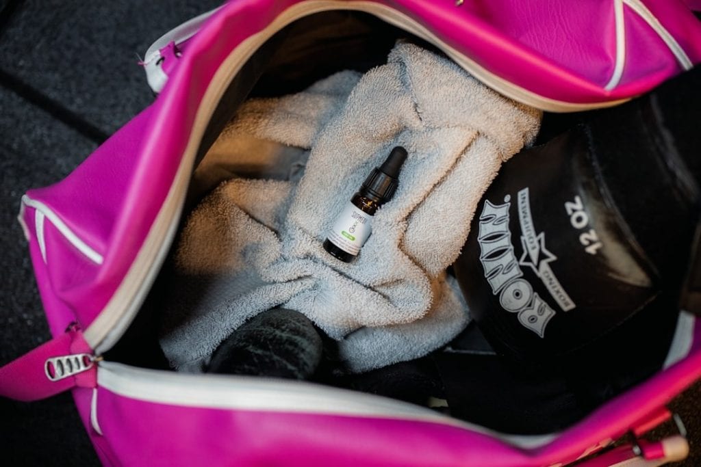 Gym bag with fitness essentials including a small bottle of essential oil, towel, and workout access.
