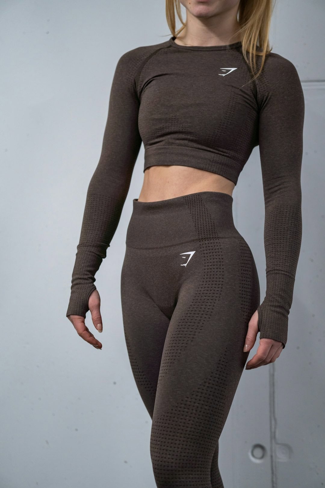 Woman in dark athletic crop top and leggings, fitness, workout, activewear.