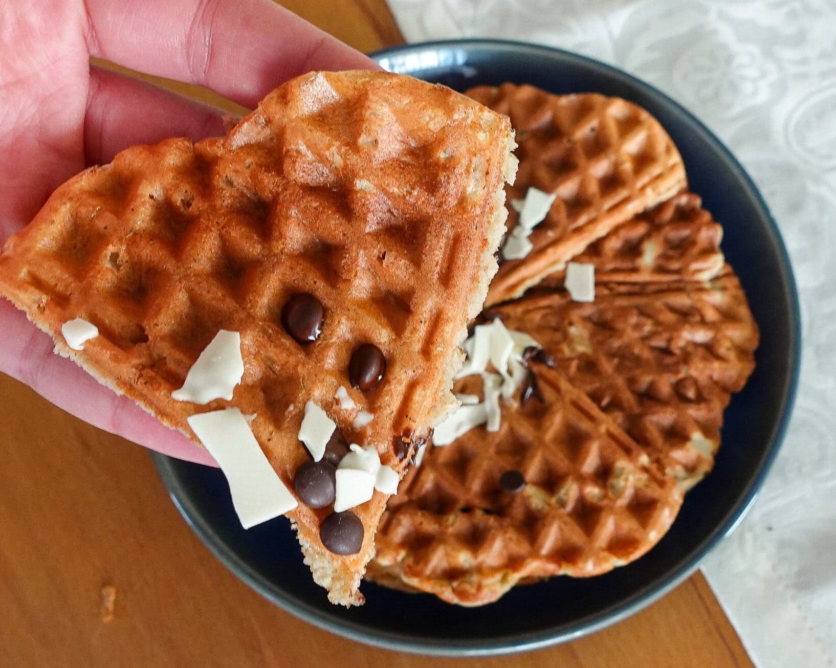 Close-up of a waffle with chocolate chips and white chocolate shavings.