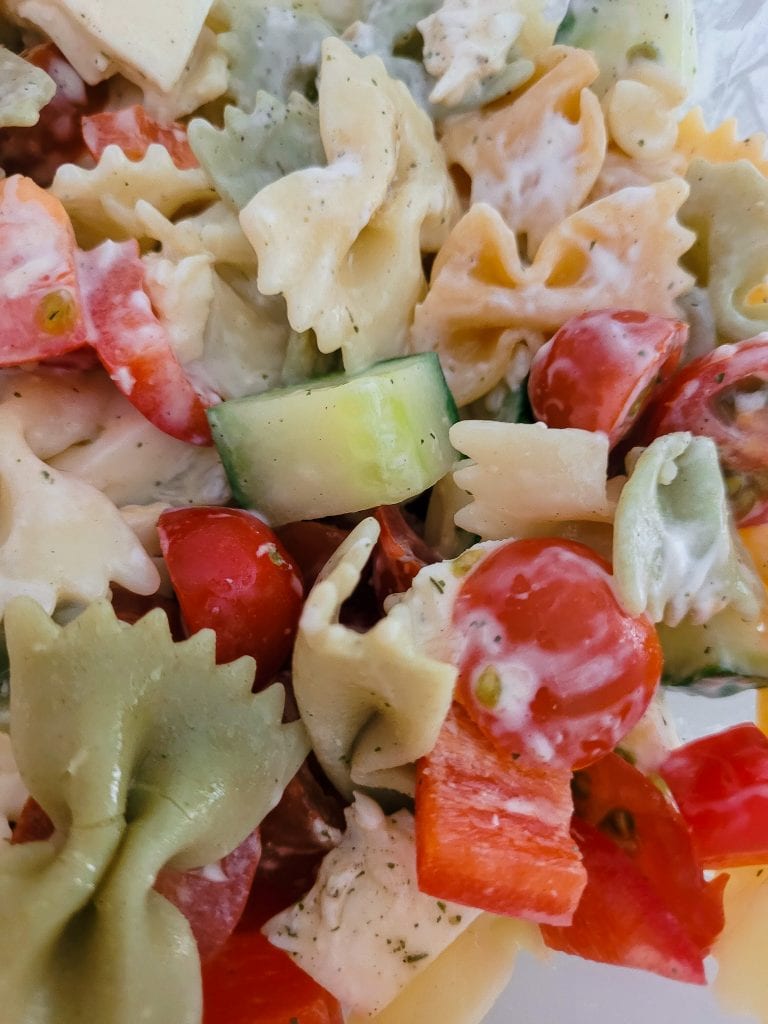 Vibrant pasta salad with cherry tomatoes, cucumbers, and mixed pasta varieties.