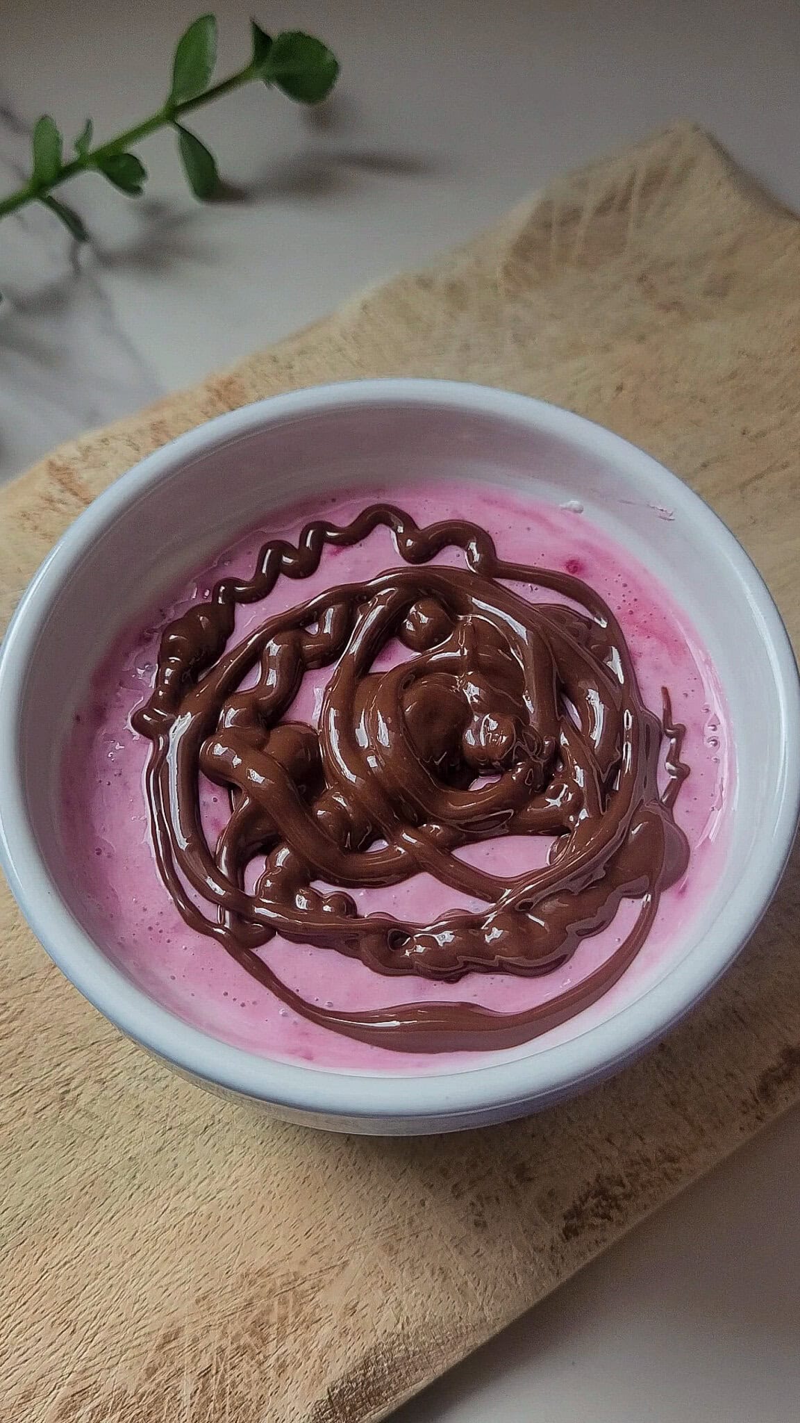 Creamy pink Greek yogurt dessert topped with chocolate drizzle and swirl.