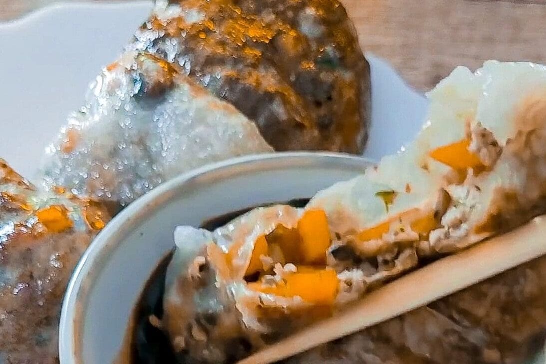 Fresh rice paper dumpling with vegetables and soy sauce on a plate.