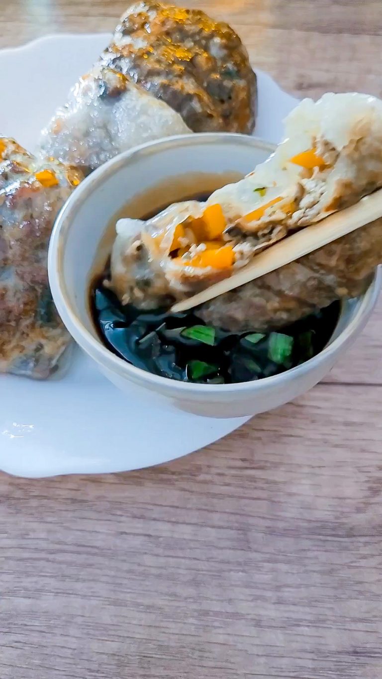 Close-up of steamed Asian dumplings with filling and dipping sauce.