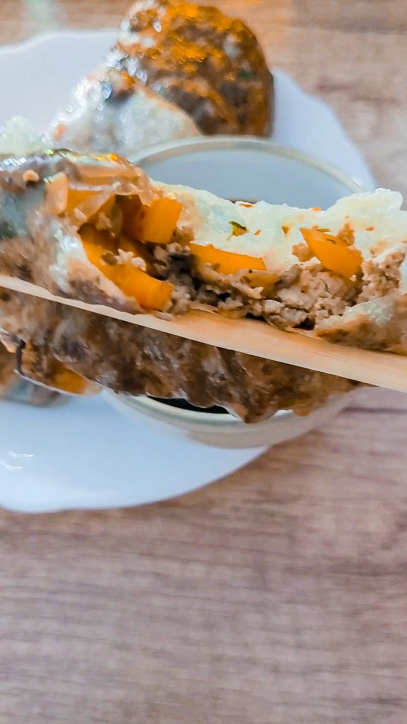 Close-up of stuffed dumpling with carrots and tofu on a wooden table.