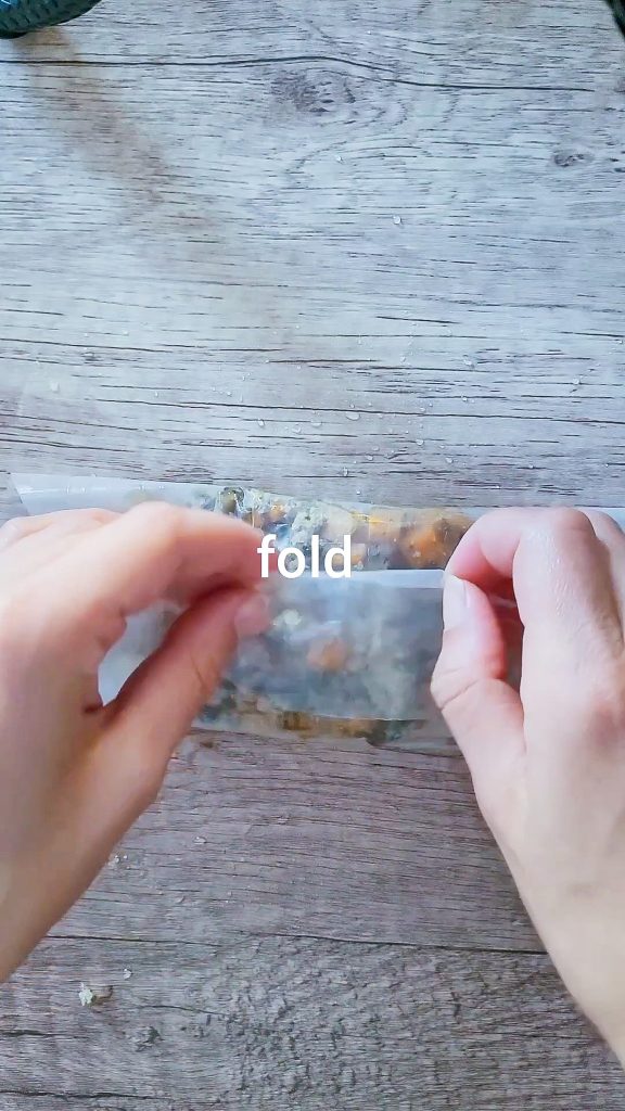 picture showing how to fold the dumpling by having the filling in the center of the wet rice paper and folding the upper and lower side  of the paper in