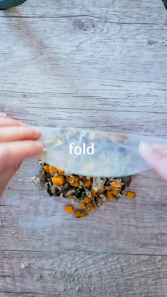 picture showing how to fold the dumpling by having the filling in the center of the wet rice paper and folding the upper side of the paper in
