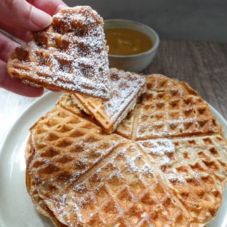 Delicious apple cinnamon waffles served with applesauce and powdered sugar.
