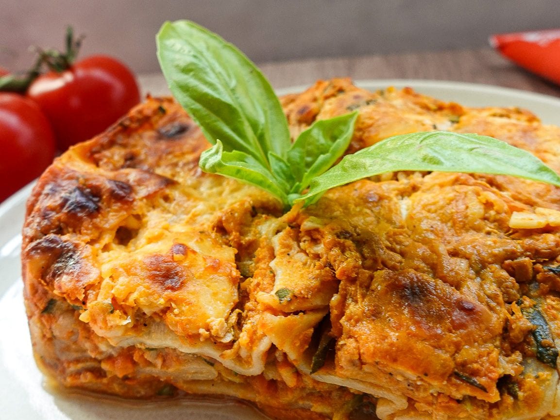 Delicious vegetable lasagna with fresh basil on top, perfect for healthy eating and fitness goals.