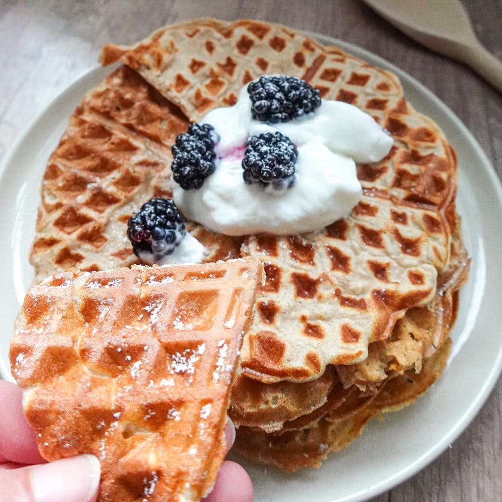Stack of waffles topped with yogurt and blackberries for a nutritious breakfast.