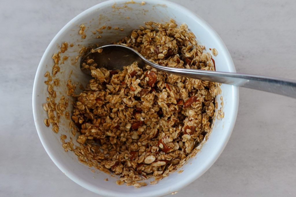 Healthy homemade granola in a white bowl with a spoon for breakfast or snack.