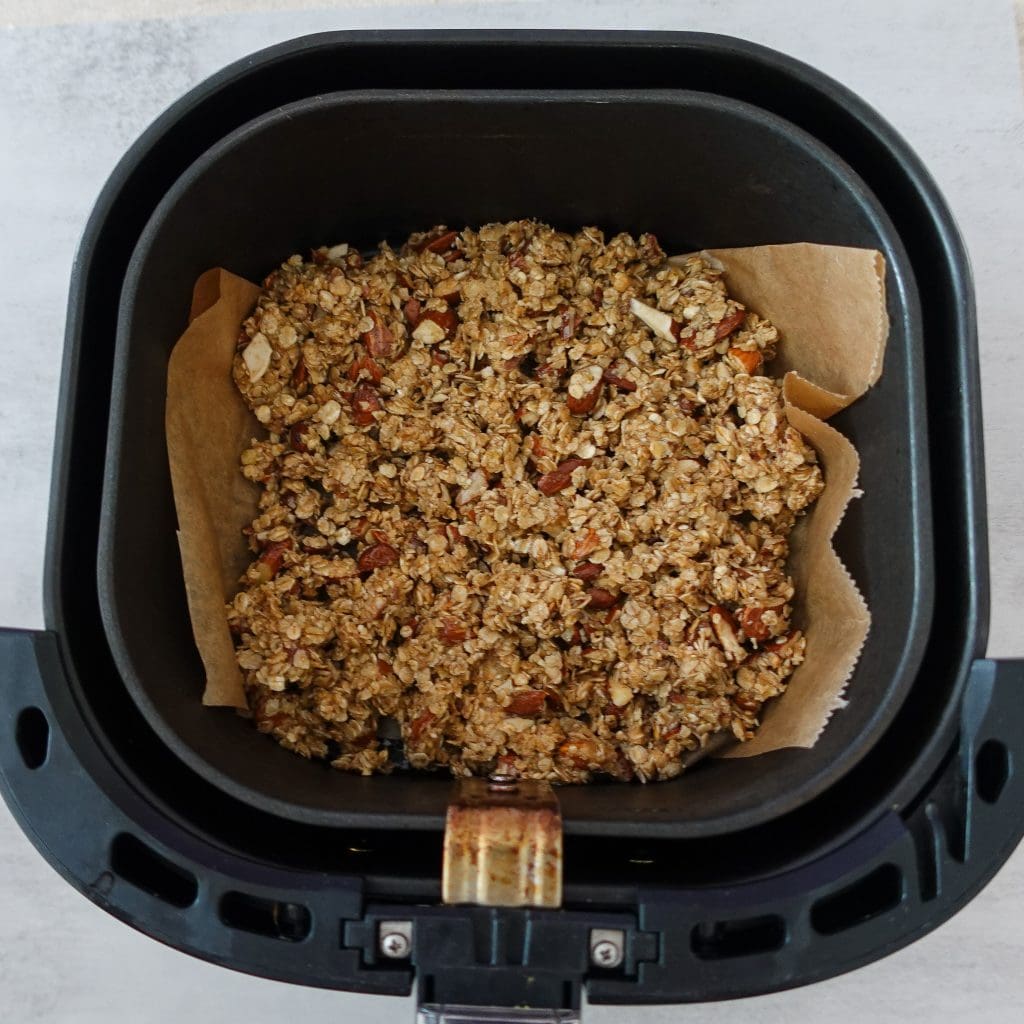 Crunchy homemade granola in air fryer with nuts and oats.