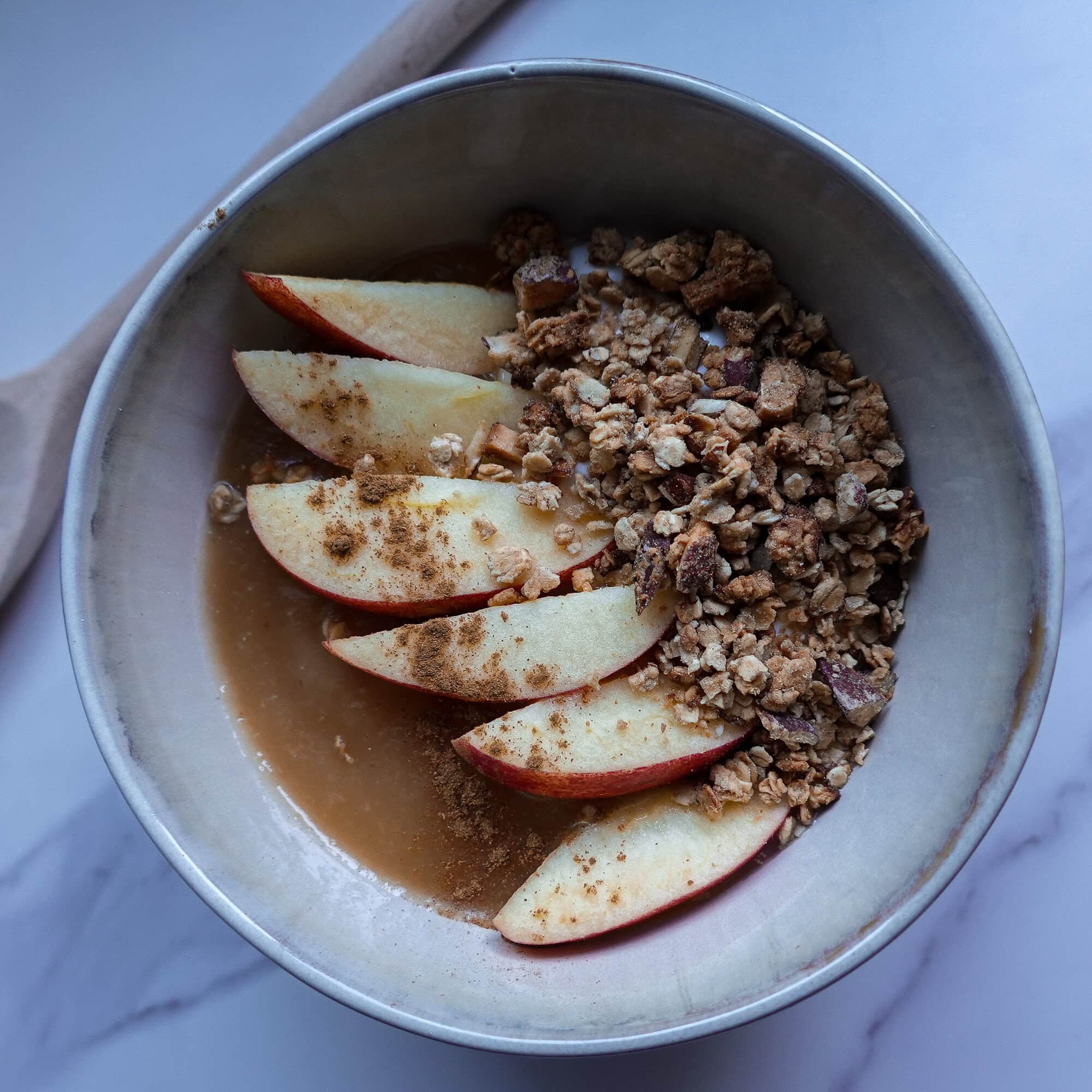 Fresh apple slices with granola and yogurt in a bowl for breakfast.