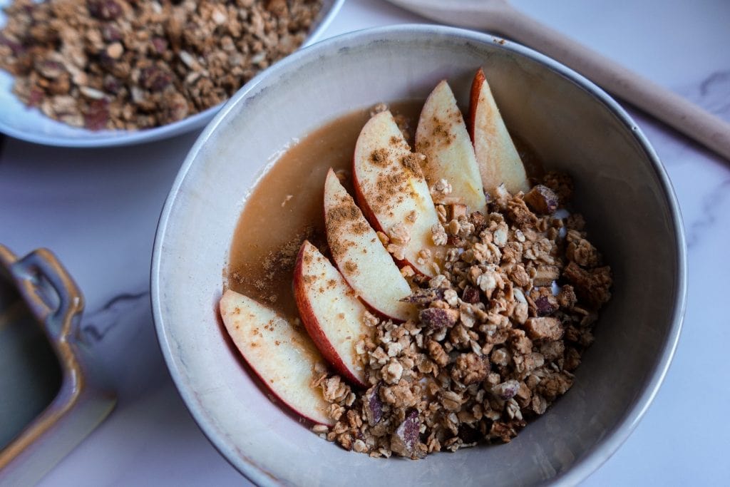 Apple slices with granola and cinnamon in a bowl for breakfast.