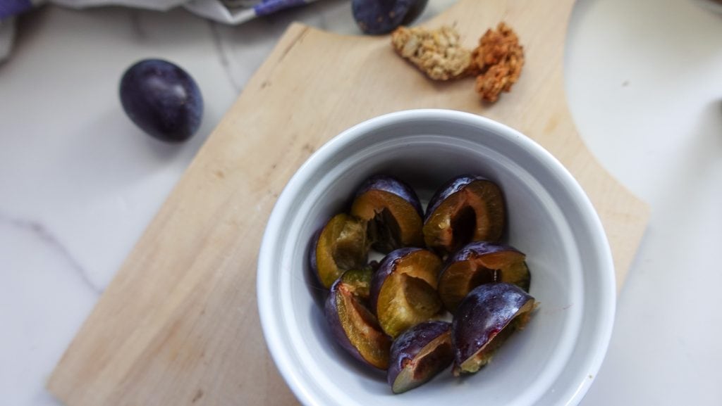 Freshly sliced plums in a white bowl for plum crumble recipe.