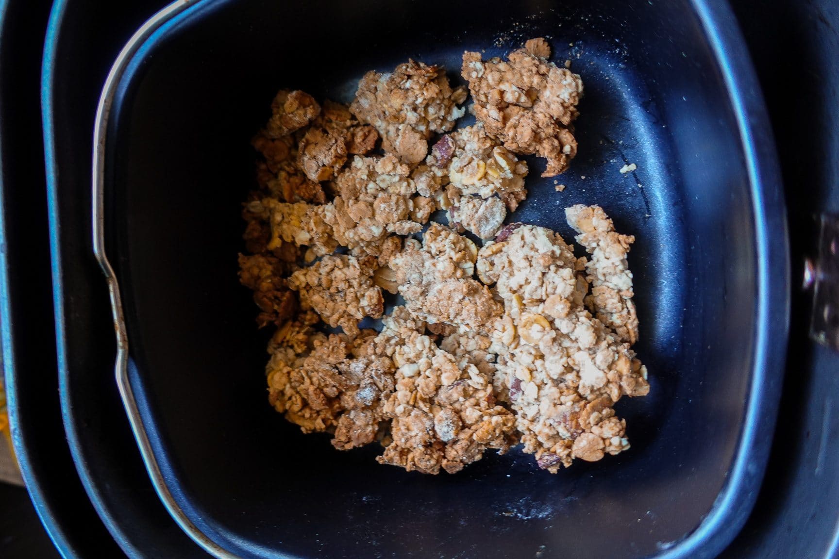 Oat crumble mixture baking in an air fryer basket.