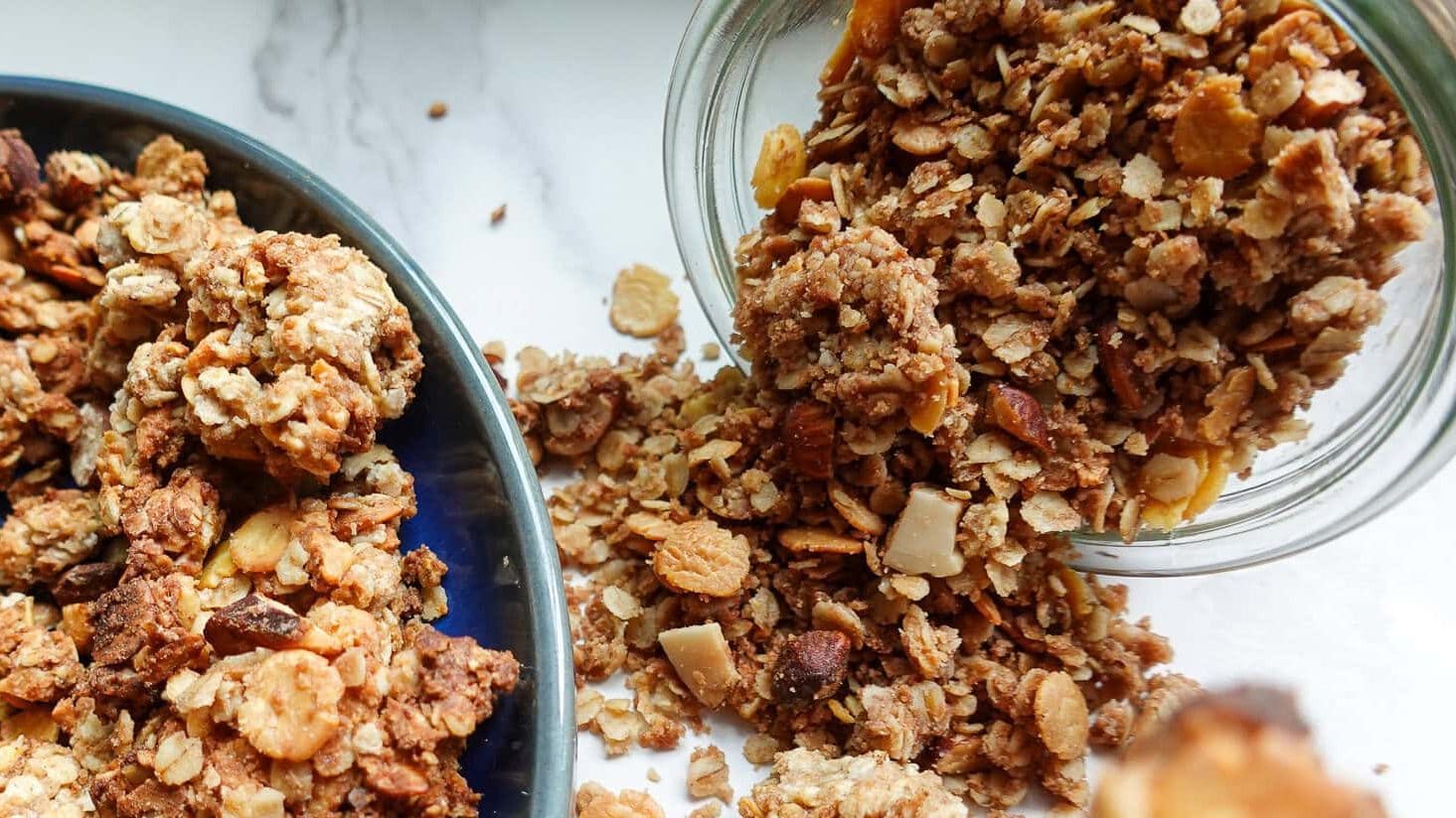 Crunchy homemade granola clusters with oats, nuts, and honey in a glass jar.