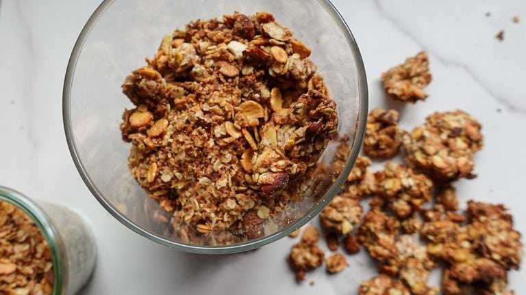 Crunchy homemade granola clusters with oats and nuts in a glass bowl.